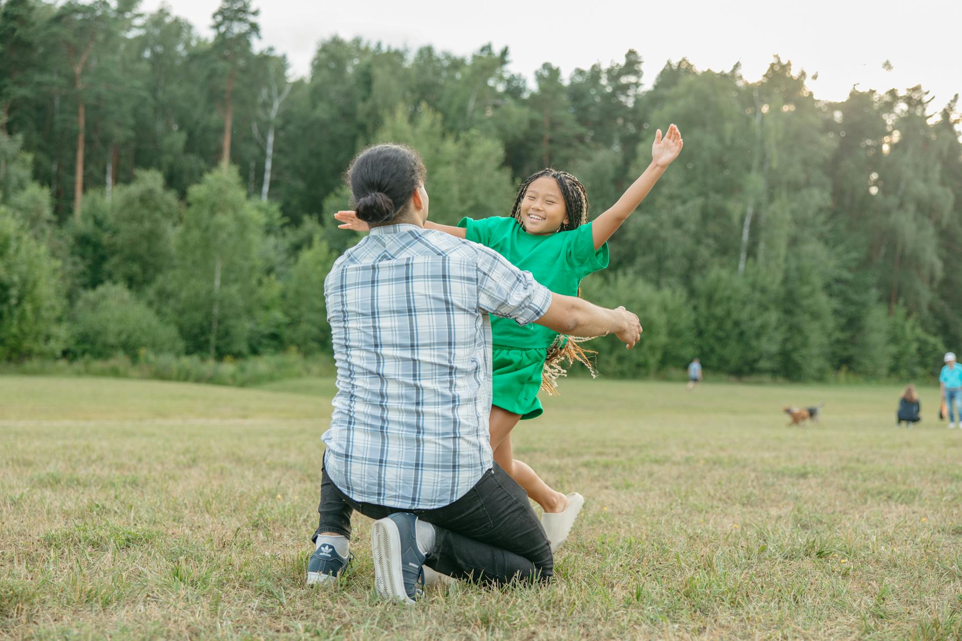 Smiling person stretching their arms outdoors in a green park.